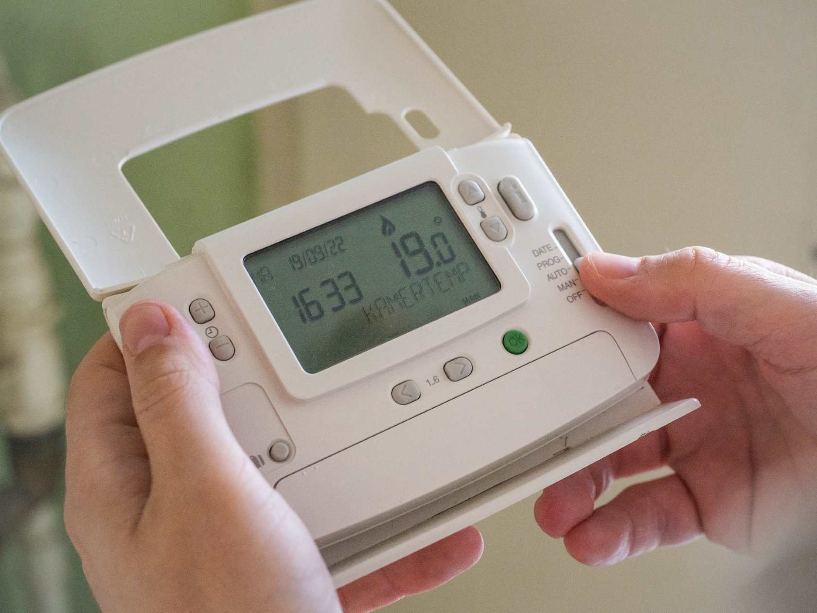 White remote controller for a heat pump being held by two hands