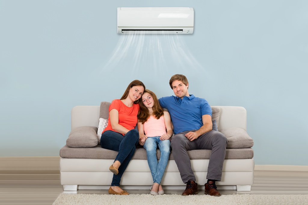 Family sitting on couch under a wall mounted heat pump.